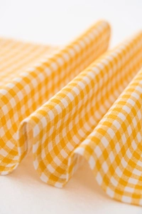 Detailed close-up of yellow and white checkered fabric with elegant soft draping and texture