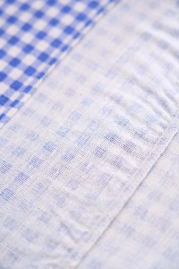 Détail de nappe à carreaux bleus montrant la texture du lin tissé et l'ourlet à volants