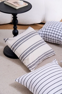 Close-up of minimalist geometric pillow covers with striped and grid patterns in a modern room
