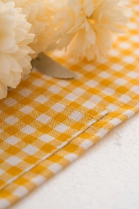 Close-up of yellow plaid dust cover fabric showing high-quality stitching and seam detail