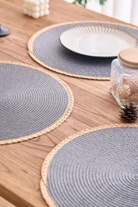 Close-up of minimalist round woven placemats with grey centers and natural fringe