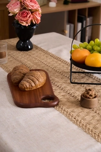 Close-up of fresh croissants on a rustic wooden bread board with a linen tablecloth
