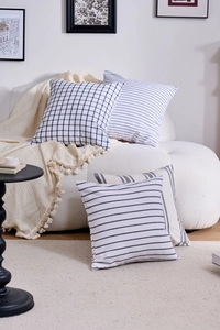 Detail of four geometric black and white patterned pillow covers on a cozy sofa