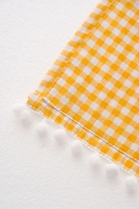 Macro detail of yellow checkered refrigerator cover with white pom-pom decorative edges