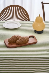 Detail of croissants on a rectangular solid wood tray over green striped tablecloth