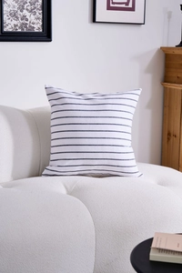 Detail of navy blue striped square pillow cover on a modern white textured sofa