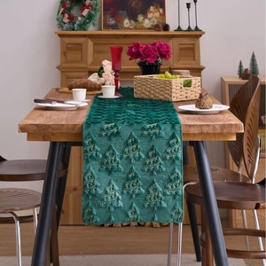 Dark green Christmas table runner with plush tree embroidery and golden stars on wood table