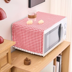 Red checkered dust cover for microwave with white fringe pom poms in a home setting