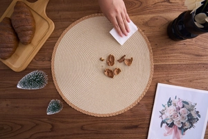 Close-up showing the easy clean surface of a woven round placemat with a paper towel
