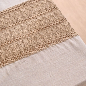 Linen tablecloth with contrast hollow crochet lace trim on light wood background