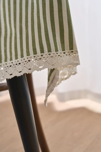 Close-up of green and white striped cotton tablecloth with elegant lace edge trim