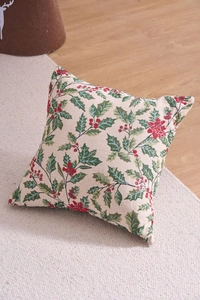 Detail view of woven Christmas jacquard pillow featuring green leaves and red berries