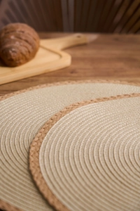 Macro detail of round woven paper placemat with dark contrast piping on wooden table