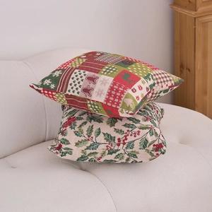 Set of two Christmas themed decorative pillows with holiday patterns on a white fabric sofa