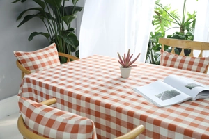Detalle del mantel de cuadros naranja y blanco con fundas de silla a juego en estilo hogar