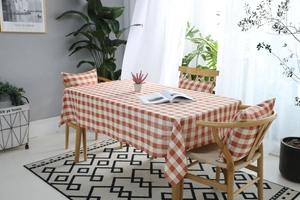 Detalle del mantel de cuadros naranja y blanco y fundas de cojín con textura tejida