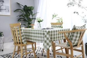 Detalle del mantel de cuadros verdes y blancos con cojín a juego en un ambiente acogedor