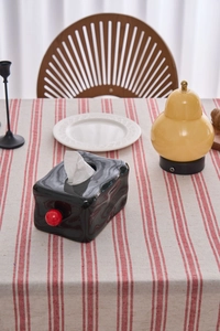 Modern black glossy tissue box with red knob on a red and white striped linen tablecloth