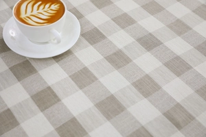 Detalle del mantel de cuadros beige y blanco de algodón y lino con una taza de café
