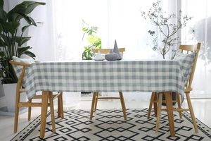 Detalle del mantel a cuadros azules y blancos con cojín a juego en comedor luminoso y moderno