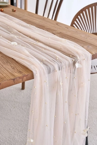 Detailed texture of pink mesh table runner with white 3D flowers and pearl beads