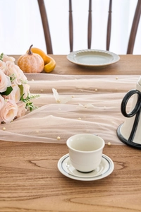 Detail of elegant lace table runner with white pearl beads on vintage wood table surface