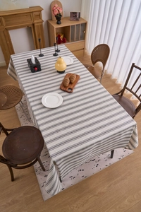 Detail of grey and white striped linen tablecloth on wooden table with dining props