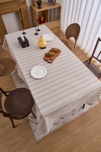 Top view of beige cotton linen tablecloth with light brown stripes on a dining table