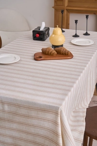 Close-up of beige linen tablecloth with brown stripes showing natural fabric texture