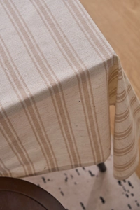 Close-up of beige cotton linen tablecloth with light brown stripes and natural texture