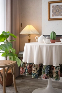 Detail of cream round tablecloth with vintage floral ruffle trim in a cozy home setting
