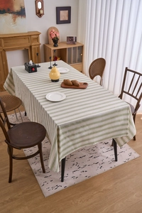 Close-up detail of green striped cotton linen tablecloth with natural texture and neat hem