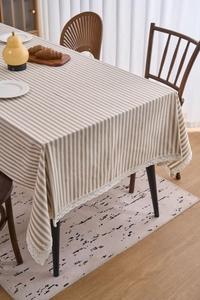 Detailed view of beige and white striped tablecloth with delicate white lace border trim