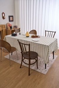 Close-up of green and beige striped linen blend tablecloth in a cozy home dining setting