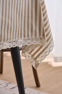 Detail of striped cotton table cloth with elegant beige lace trim and rustic fabric texture