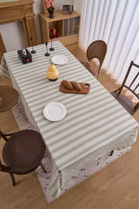 Macro shot of green and beige striped cotton linen tablecloth on a rectangle table
