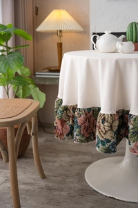 Detailed close-up of beige round tablecloth with vintage floral jacquard ruffle trim finish