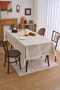 Detailed close-up of light brown striped tablecloth with elegant white crochet lace trim