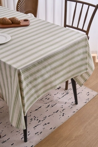 Detail of green striped cotton linen tablecloth draped over a wooden dining table
