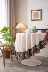 Close-up of beige round tablecloth featuring vintage floral jacquard ruffle hem and fabric detail
