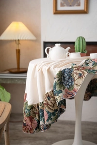 Detail of vintage floral jacquard pattern and ruffled edges on an ivory round tablecloth