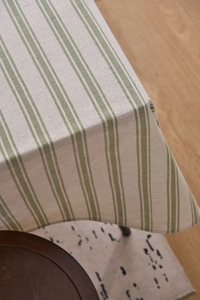 Detail of green striped linen tablecloth showing fabric texture and natural drape