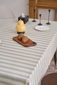 Detailed texture of green and beige striped linen tablecloth on a wooden table surface