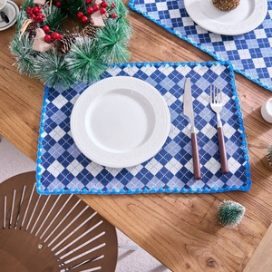 Blue and white plaid fabric placemat with crochet lace border on a wooden table