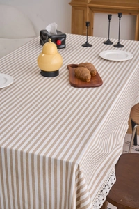 Close-up of khaki and white striped tablecloth with delicate white lace edge detail