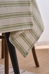 Close-up of green and white striped cotton linen tablecloth with thick texture and hemmed edge