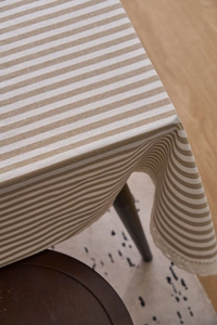 Detail of khaki striped tablecloth featuring delicate white lace trim and cotton linen texture