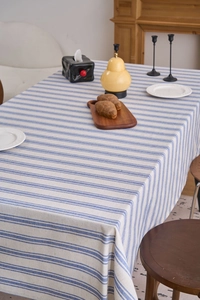 Detail of blue and beige striped cotton linen tablecloth with lace edges on table