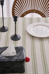 Macro detail of natural cotton linen striped tablecloth with green accents on a dining table
