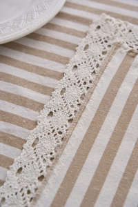 Close-up of striped polyester cotton tablecloth with elegant lace border and linen texture